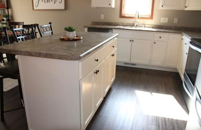 2007 Pratt Cir, Saint Peter, MN 56082 - kitchen with a kitchen island, dark wood-style floors, dark countertops, and white cabinets