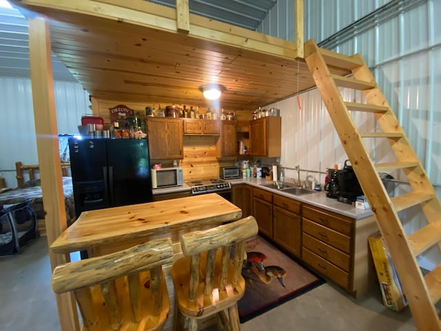 20668 County Road 41, Bremen Twp, MN 55795 - kitchen featuring stainless steel microwave, black refrigerator with ice dispenser, brown cabinetry, range with electric cooktop, and butcher block countertops