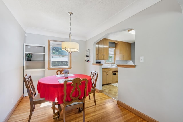 3355 Central Ave NE, Minneapolis, MN 55418 - dining area featuring light wood finished floors, healthy amount of natural light, arched walkways, and a textured ceiling