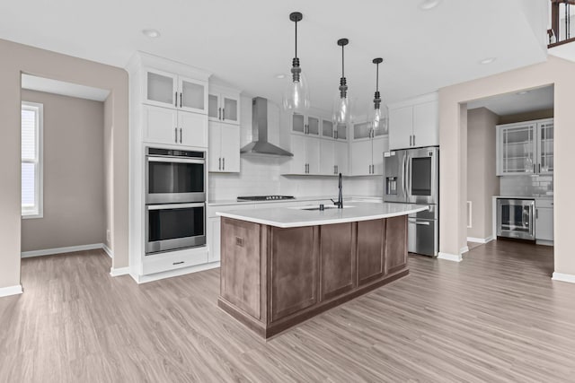 5390 Everest Ln N, Plymouth, MN 55446 - kitchen featuring wall chimney exhaust hood, appliances with stainless steel finishes, light countertops, decorative backsplash, and light wood-style flooring