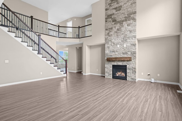 5390 Everest Ln N, Plymouth, MN 55446 - unfurnished living room with a towering ceiling, wood finished floors, stairway, and a stone fireplace