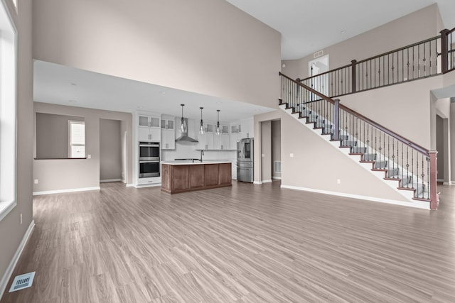 5390 Everest Ln N, Plymouth, MN 55446 - unfurnished living room featuring a high ceiling, light wood-type flooring, and stairway