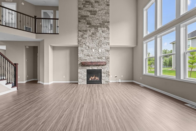 5390 Everest Ln N, Plymouth, MN 55446 - unfurnished living room with a high ceiling, wood finished floors, stairs, and a fireplace