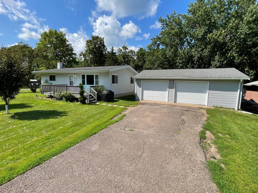 504 Linden St W, Frederic, WI 54837 - single story home with an outbuilding, a front yard, a wooden deck, a chimney, and a detached garage