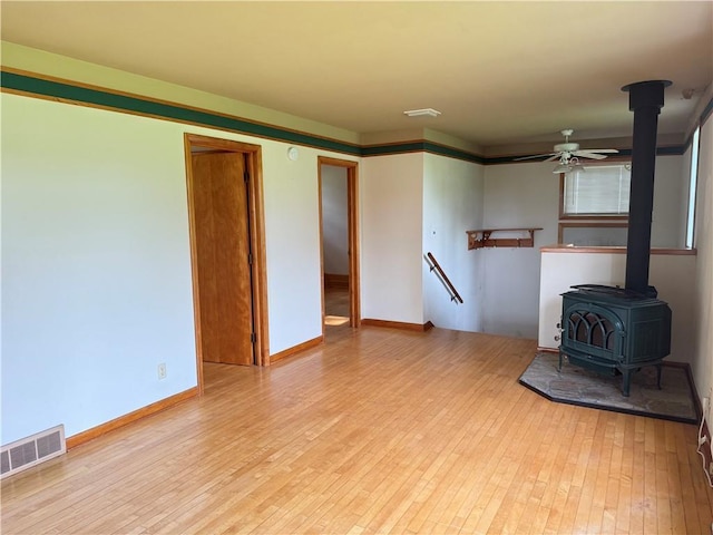 2999 18th St, Oak Grove Twp, WI 54868 - unfurnished living room with a wood stove, light wood finished floors, and ceiling fan