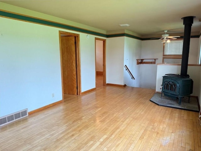 2999 18th St, Oak Grove Twp, WI 54868 - unfurnished living room featuring a wood stove, hardwood / wood-style floors, and a ceiling fan