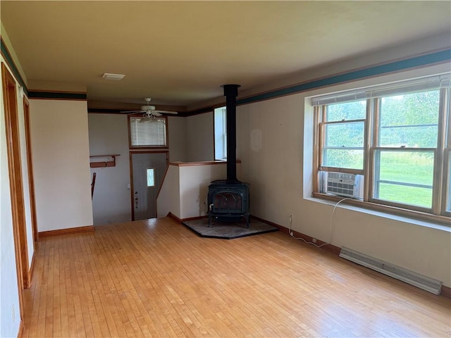 2999 18th St, Oak Grove Twp, WI 54868 - unfurnished living room featuring baseboard heating, a wood stove, plenty of natural light, and cooling unit