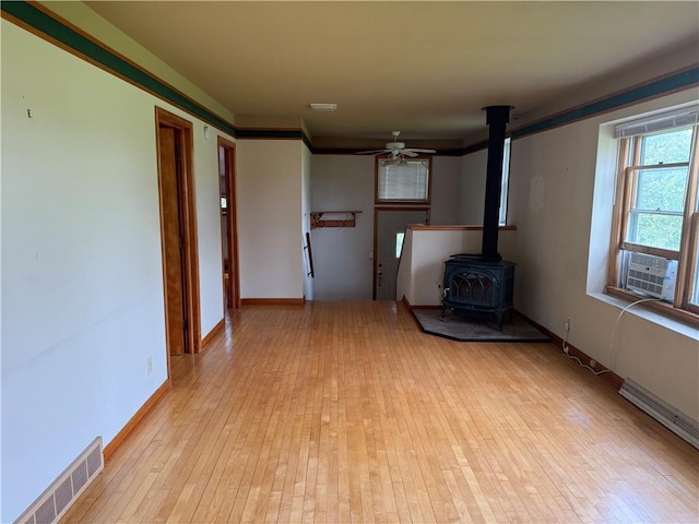2999 18th St, Oak Grove Twp, WI 54868 - unfurnished living room featuring a wood stove, cooling unit, light wood finished floors, and a ceiling fan