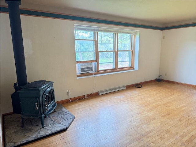 2999 18th St, Oak Grove Twp, WI 54868 - empty room featuring a wood stove, cooling unit, hardwood / wood-style flooring, and baseboard heating
