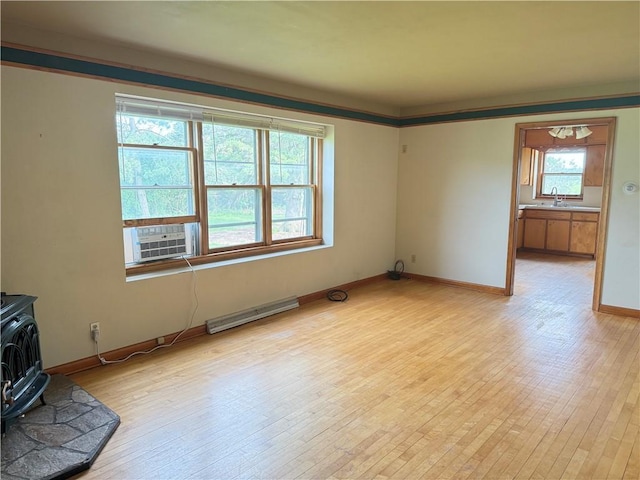2999 18th St, Oak Grove Twp, WI 54868 - unfurnished living room with a wood stove, cooling unit, light wood-type flooring, and a baseboard heating unit