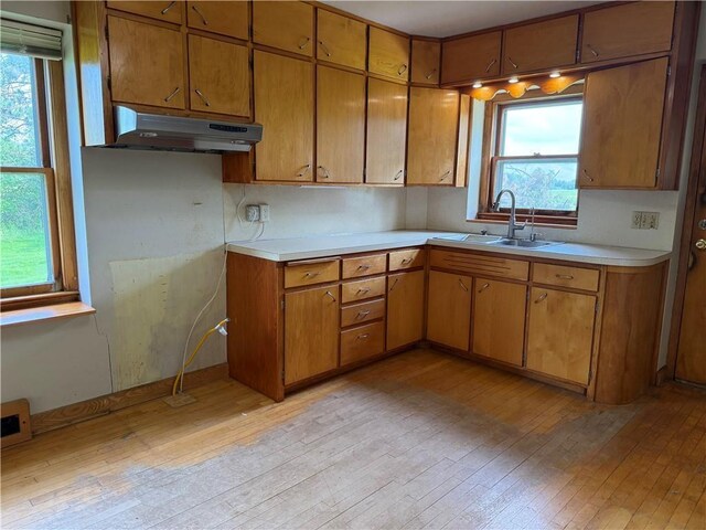 2999 18th St, Oak Grove Twp, WI 54868 - kitchen with light wood-style floors, under cabinet range hood, light countertops, and brown cabinetry