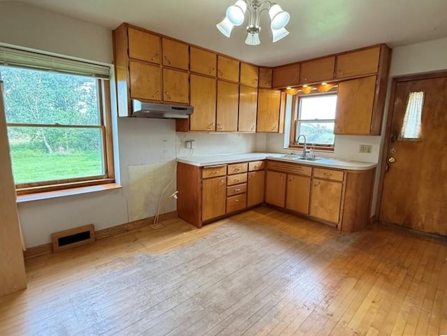 2999 18th St, Oak Grove Twp, WI 54868 - kitchen with under cabinet range hood, light wood finished floors, light countertops, and brown cabinetry