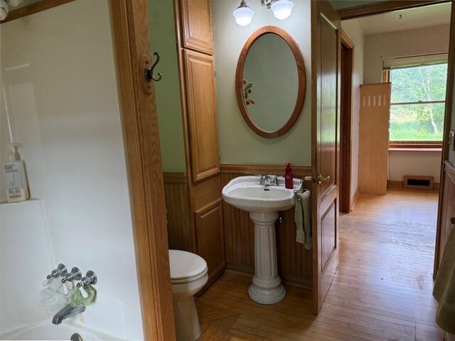 2999 18th St, Oak Grove Twp, WI 54868 - bathroom with a wainscoted wall, a tub, and wood finished floors
