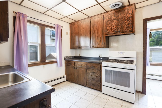 2707 Girard Ave N, Minneapolis, MN 55411 - kitchen with white range with gas cooktop, baseboard heating, dark countertops, and light tile patterned floors