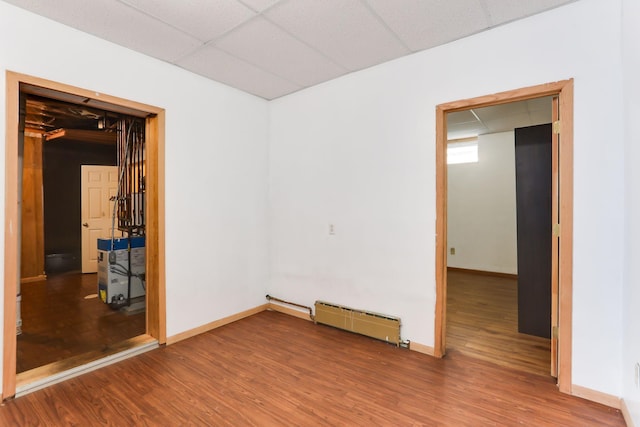2707 Girard Ave N, Minneapolis, MN 55411 - spare room with a baseboard heating unit, wood finished floors, and a drop ceiling