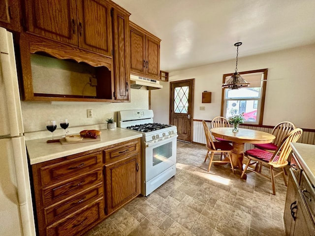 7520 14th Ave S, Richfield, MN 55423 - kitchen featuring white appliances, light countertops, under cabinet range hood, brown cabinetry, and pendant lighting