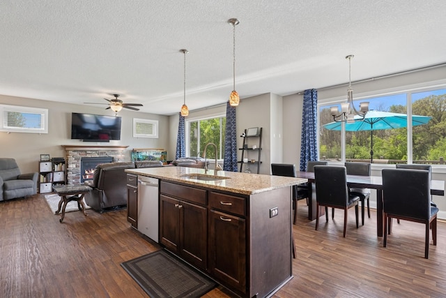 24000 Helium Ct, Forest Lake, MN 55025 - kitchen featuring a stone fireplace, dark wood finished floors, dark brown cabinets, a ceiling fan, and decorative light fixtures