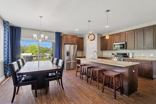 24000 Helium Ct, Forest Lake, MN 55025 - kitchen featuring stainless steel appliances, a chandelier, a center island with sink, dark wood-style flooring, and a kitchen bar