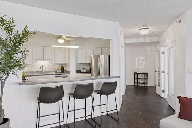168 6th St E Unit 3004, Saint Paul, MN 55101 - kitchen featuring freestanding refrigerator, a breakfast bar area, backsplash, a peninsula, and a textured ceiling