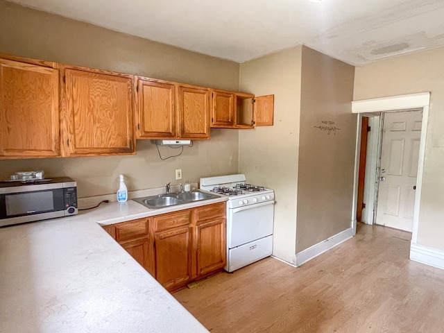 629 Farrington St, Saint Paul, MN 55103 - kitchen featuring gas range gas stove, stainless steel microwave, light countertops, light wood-style floors, and brown cabinetry