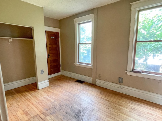 629 Farrington St, Saint Paul, MN 55103 - unfurnished bedroom featuring wood-type flooring, multiple windows, and a textured ceiling