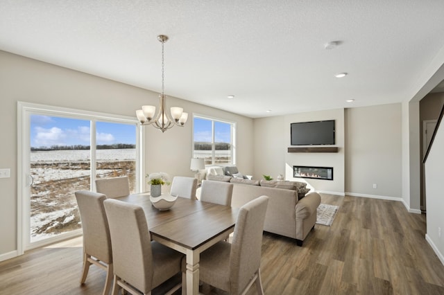 757 Greywood Blvd SW, Delano, MN 55328 - dining space with wood finished floors, a chandelier, a glass covered fireplace, and recessed lighting