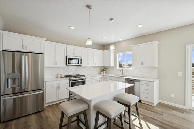 757 Greywood Blvd SW, Delano, MN 55328 - kitchen featuring appliances with stainless steel finishes, wood finished floors, a breakfast bar, tasteful backsplash, and recessed lighting