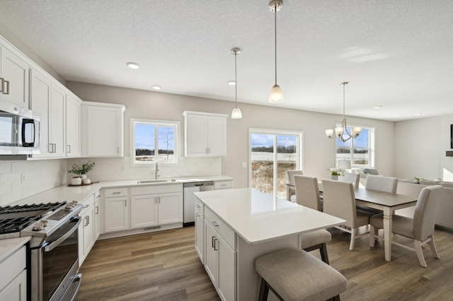 757 Greywood Blvd SW, Delano, MN 55328 - kitchen with appliances with stainless steel finishes, decorative backsplash, a chandelier, a breakfast bar, and a textured ceiling