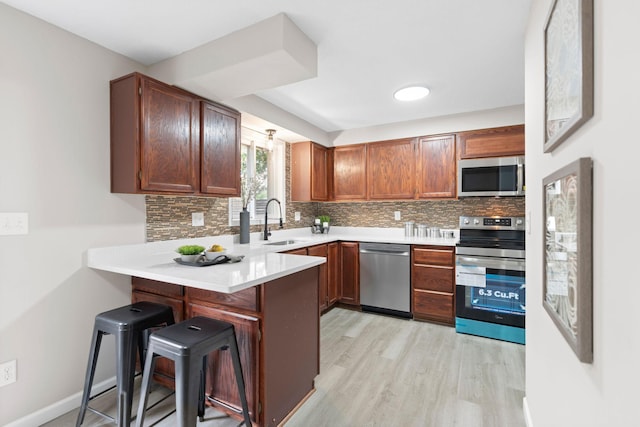 6494 Bonner Ct, Inver Grove Heights, MN 55076 - kitchen with appliances with stainless steel finishes, a peninsula, light wood-type flooring, and tasteful backsplash