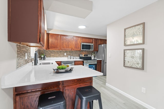 6494 Bonner Ct, Inver Grove Heights, MN 55076 - kitchen with appliances with stainless steel finishes, light wood-style flooring, decorative backsplash, a breakfast bar area, and a peninsula