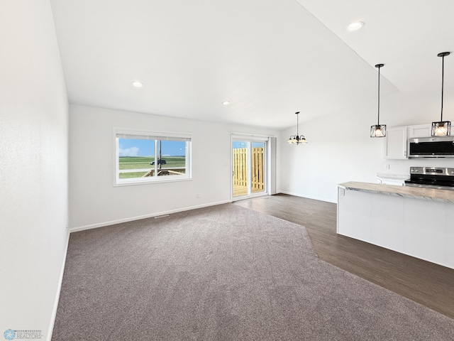 4832 51st Ave S, Fargo, ND 58104 - unfurnished living room with a chandelier, dark wood-style flooring, vaulted ceiling, recessed lighting, and dark carpet