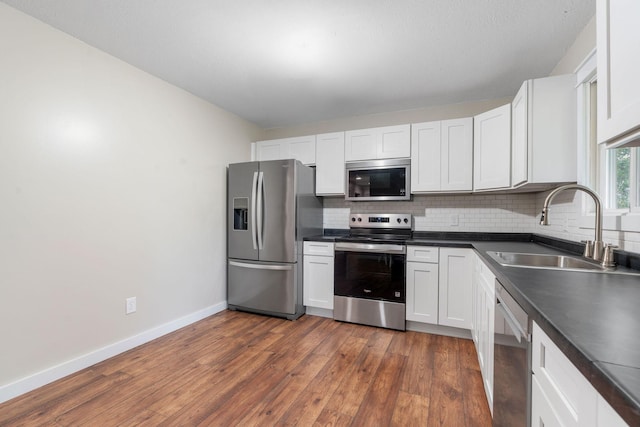540 4th St E, Wanamingo, MN 55983 - kitchen with stainless steel appliances, decorative backsplash, dark countertops, and dark wood-style floors