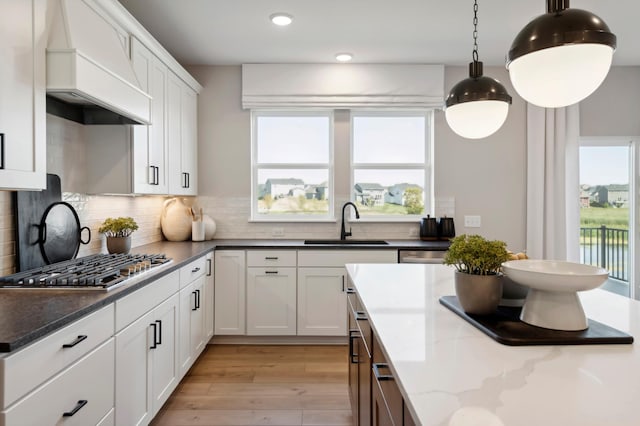 14540 106th Pl N, Maple Grove, MN 55369 - kitchen with stainless steel gas stovetop, premium range hood, light wood-style floors, backsplash, and healthy amount of natural light