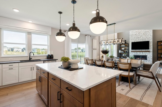 14540 106th Pl N, Maple Grove, MN 55369 - kitchen with light wood-style floors, a kitchen island, a fireplace, white cabinetry, and recessed lighting