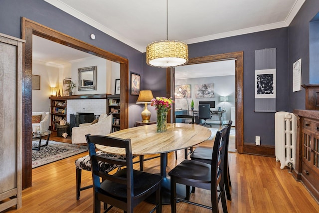 2612 52nd St, Minneapolis, MN 55410 - dining area featuring a brick fireplace, wood finished floors, radiator heating unit, and ornamental molding