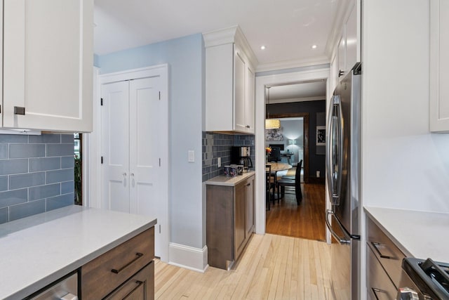 2612 52nd St, Minneapolis, MN 55410 - kitchen with light wood-style flooring, freestanding refrigerator, backsplash, white cabinetry, and recessed lighting