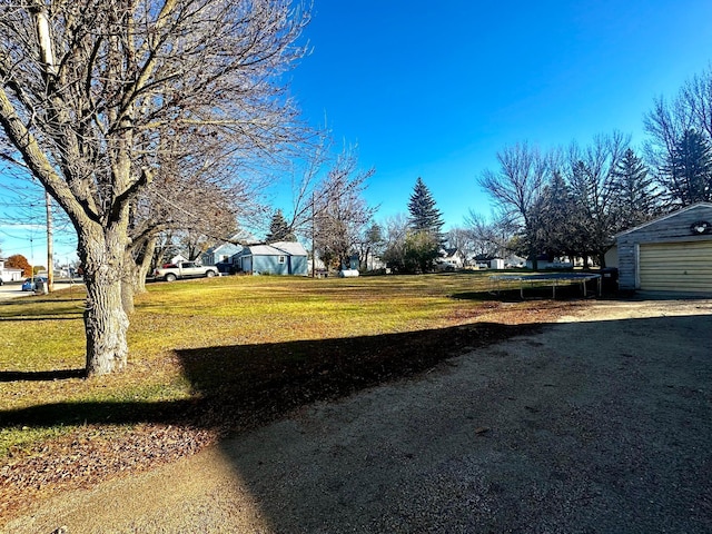 2716 Canterbury Dr, Bigelow, MN 56117 - view of grassy yard with an outdoor structure, a trampoline, and a garage