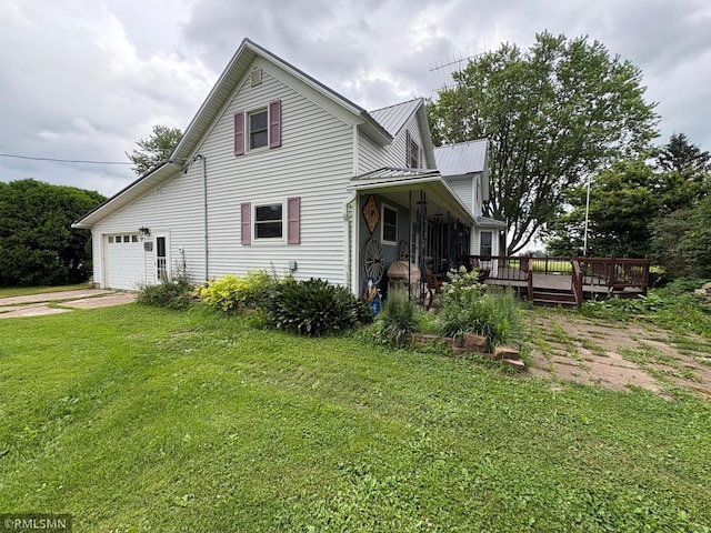 W5168 Lake Rd, Warner Twp, WI 54437 - view of property exterior featuring driveway, a lawn, a garage, a metal roof, and a wooden deck