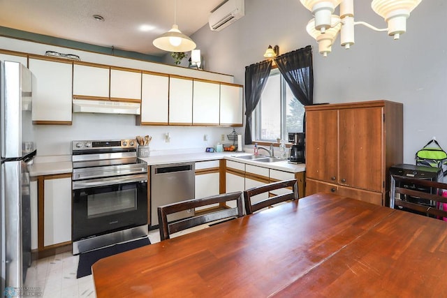 1426 11th St W, West Fargo, ND 58078 - kitchen featuring stainless steel appliances, under cabinet range hood, a wall unit AC, a chandelier, and white cabinetry