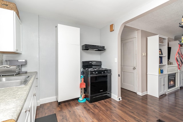1034 Carroll Ave, Saint Paul, MN 55104 - kitchen featuring black gas range, wall chimney exhaust hood, light countertops, dark wood-style floors, and arched walkways