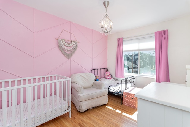 1034 Carroll Ave, Saint Paul, MN 55104 - bedroom with light wood-style floors, a chandelier, and a nursery area