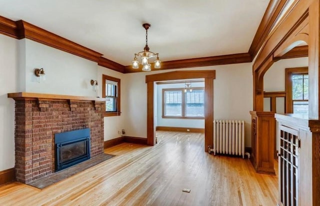 4105 Columbus Ave, Minneapolis, MN 55407 - unfurnished living room with radiator heating unit, a chandelier, light wood-style floors, a brick fireplace, and crown molding