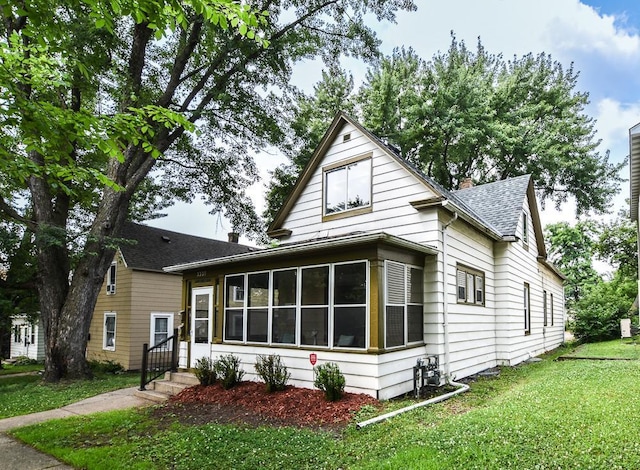 3339 Aldrich Ave N, Minneapolis, MN 55412 - view of front facade featuring a sunroom, a shingled roof, and a front yard