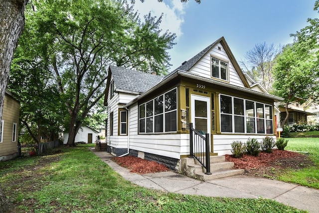 3339 Aldrich Ave N, Minneapolis, MN 55412 - bungalow-style house with a sunroom, roof with shingles, entry steps, and a front lawn