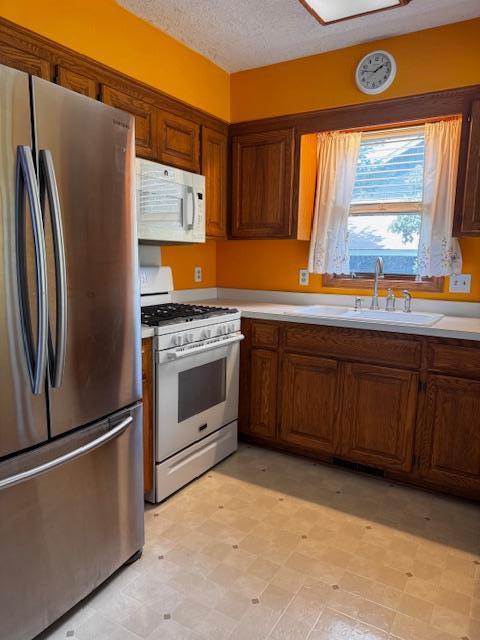 14886 Crandall Ave W, Rosemount, MN 55068 - kitchen with white appliances, a textured ceiling, brown cabinets, light countertops, and light floors