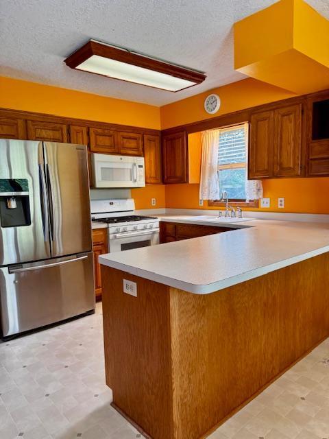 14886 Crandall Ave W, Rosemount, MN 55068 - kitchen featuring white appliances, light floors, a peninsula, light countertops, and brown cabinetry