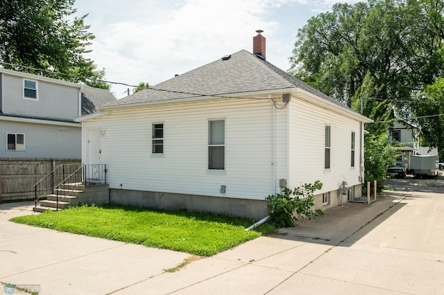 1137 11th St N, Fargo, ND 58102 - view of side of home featuring roof with shingles, a chimney, and concrete driveway
