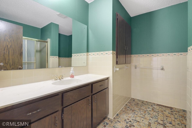 5733 Riverview Entry, Champlin, MN 55316 - bathroom featuring vanity, a shower stall, a textured ceiling, tile walls, and a wainscoted wall