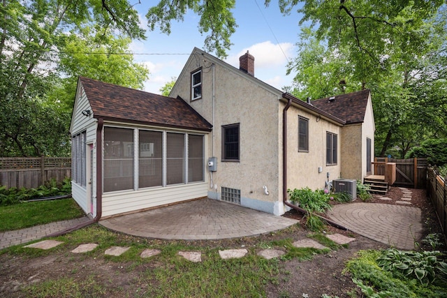 3607 Sheridan Ave N, Minneapolis, MN 55412 - rear view of property featuring a sunroom, a patio, roof with shingles, a chimney, and a fenced backyard