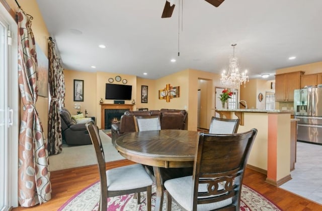 15850 Elmwood Ln, Apple Valley, MN 55124 - dining room featuring a lit fireplace, light wood-style floors, a ceiling fan, recessed lighting, and a chandelier